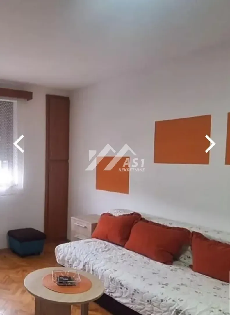 Manja dnevna soba sa kaučem, stočićem i dekoracijom na zidu.