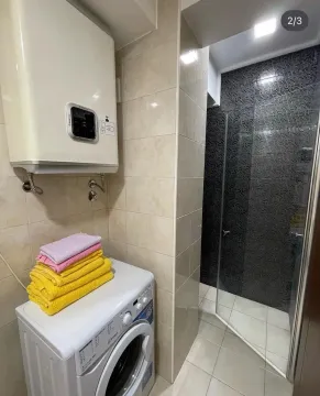 Smaller bathroom with a shower cabin, water heater, and washing machine. - image 5