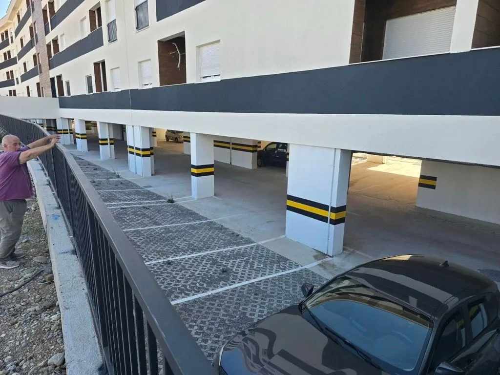 Pogled na spoljašnjost zgrade sa parkingom i prilazom.
