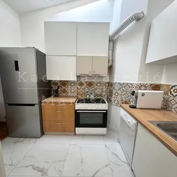 Kitchen equipped with white and wooden cabinets, a stove, and a refrigerator. - image 6
