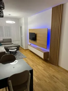 Moderan dnevni boravak sa dekorativnim zidnim panelom za televizor i trpezarijskim stolom. - image 2