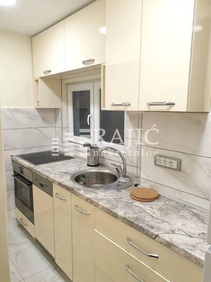 Smaller equipped kitchen with light cabinets and built-in appliances.