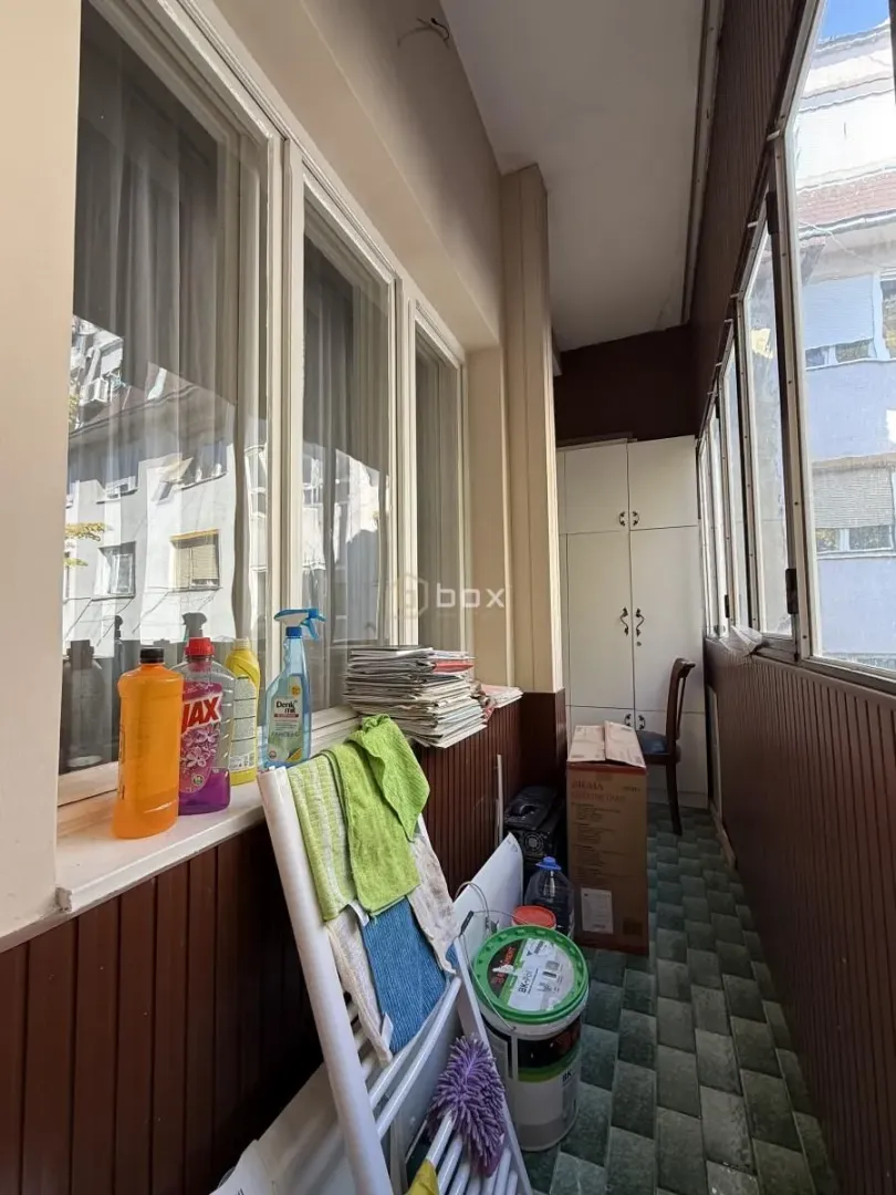 Zastakljeni balkon sa sredstvima za čišćenje i različitim predmetima.