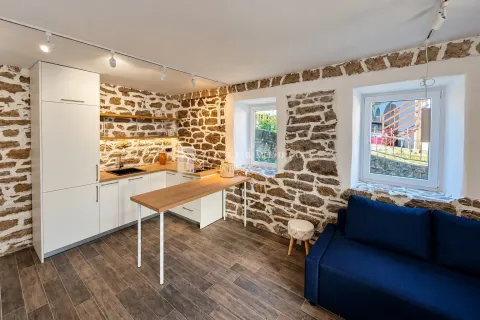 Moderna kuhinja sa šankom i ugradnim elementima uklopljena u rustični enterijer sa kamenim zidovima. - image 3