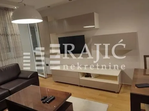 Living room with a sofa, TV unit, and dining table.