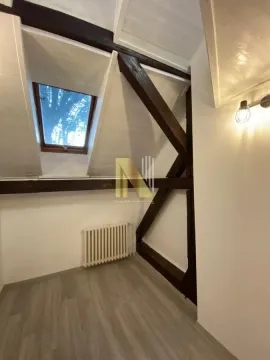 Potkrovlje sa drvenim gredama, krovnim prozorom i laminatom na podu. - image 6