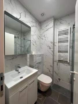 Modern bathroom equipped with white ceramic tiles and a marble pattern. - image 5