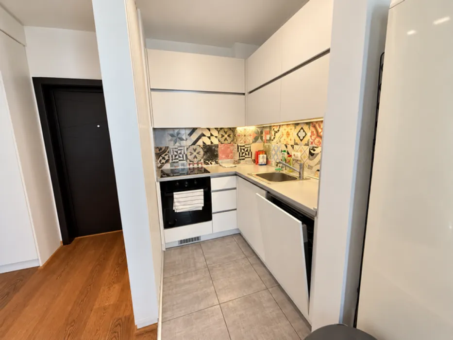 Modern white kitchen with patterned wall tiles and a built-in oven.