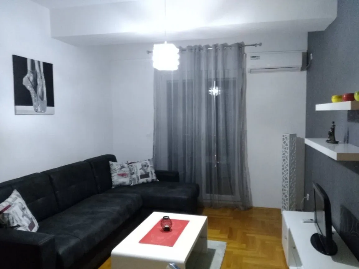 Dnevna soba sa tamnom ugaonom garniturom i bijelim klub stolom.