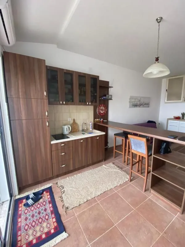 Manja kuhinja u braon tonovima sa šankom i barskim stolicama.