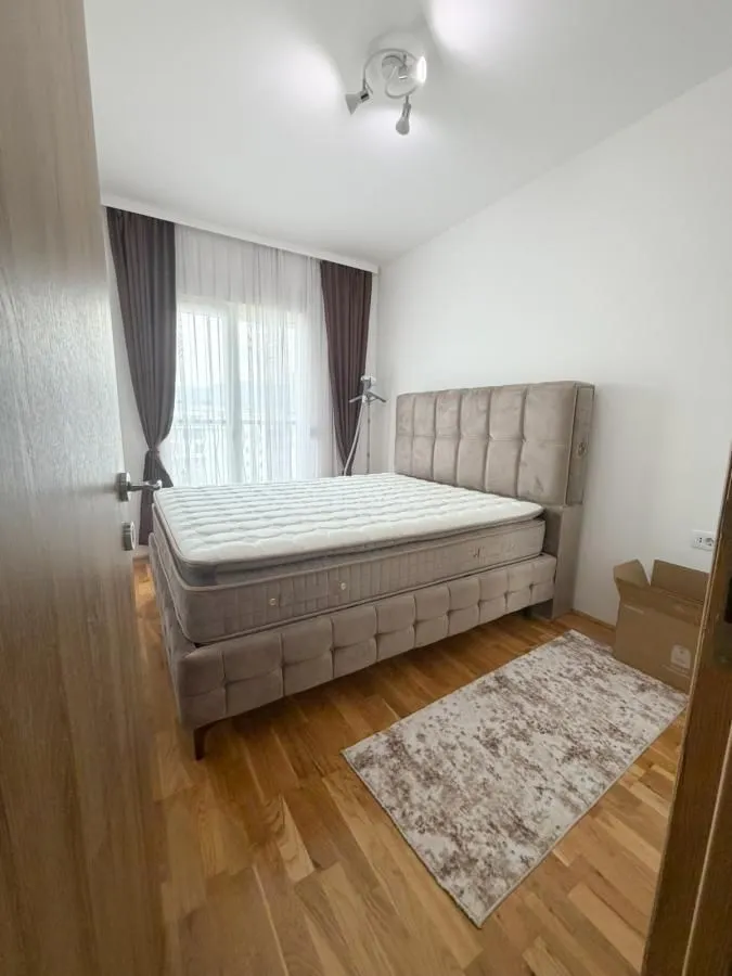 Spavaća soba sa bračnim krevetom i prozorom sa zavjesama.