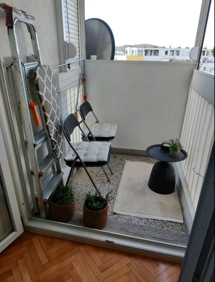 Small enclosed balcony with a table, chairs, and ladder.