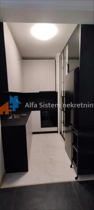 Moderna kuhinja sa crnim i belim elementima.