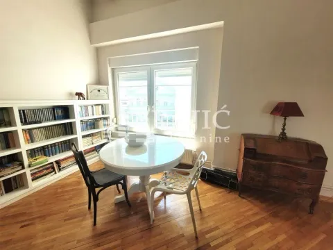 Living room with a dining table, bookshelves, and parquet flooring. - image 7