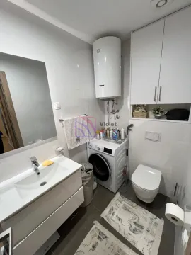 Modern bathroom with a sink, washing machine, water heater, and toilet. - image 10