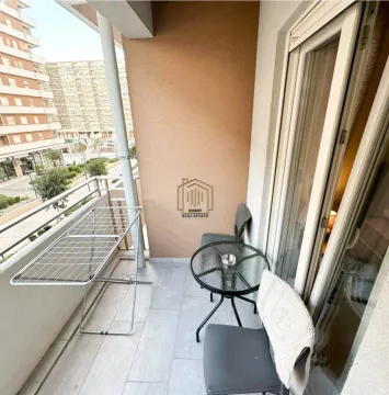 Furnished balcony with a table, chairs, and a clothes drying rack. - image 5