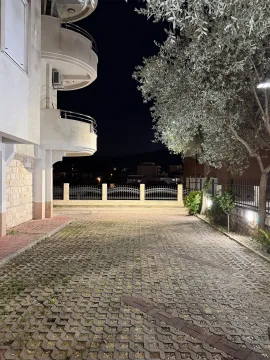 Noćni pogled na spoljašnjost zgrade sa popločanim dvorištem i maslinom. - image 12
