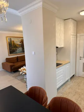 White kitchen with white cabinetry and a view of the living room. - image 15