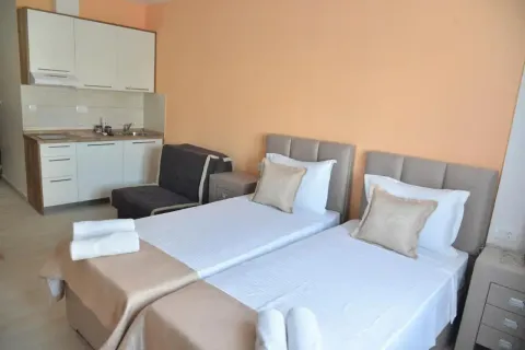 Bedroom with two single beds and a small kitchen in the background. - image 9