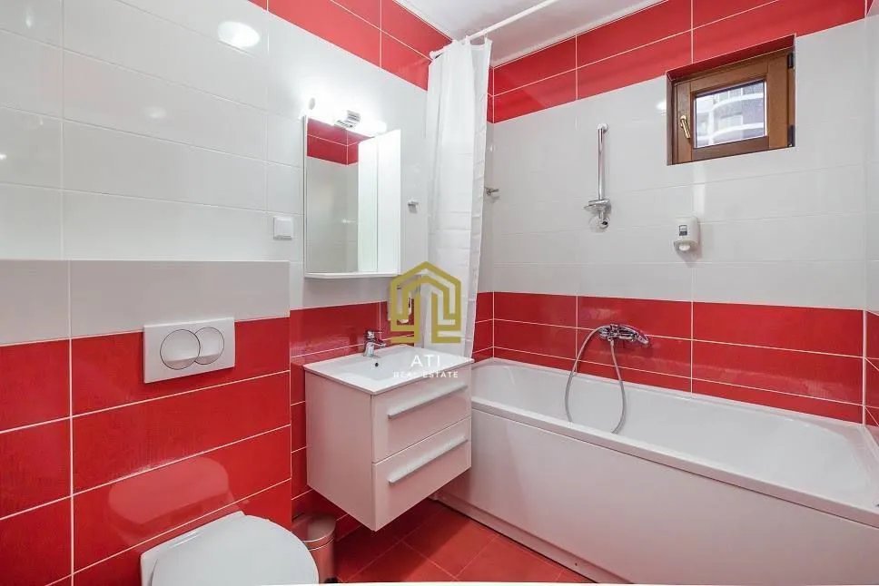 A compact bathroom with white and red tiles, a bathtub, and a sink.