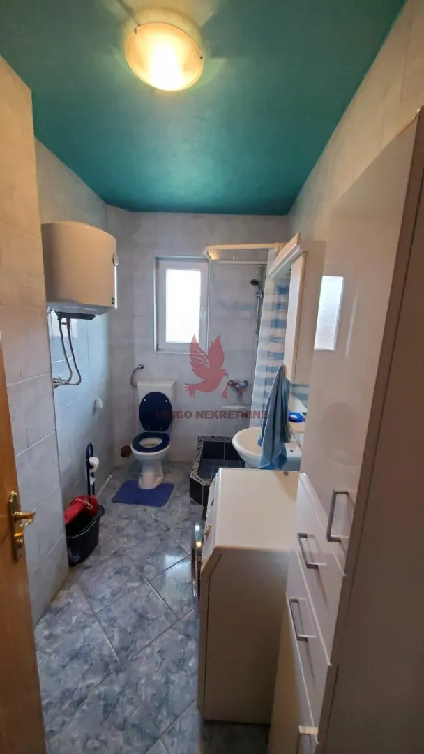 Manje kupatilo sa WC šoljom, tuš kabinom, umivaonikom i bojlerom.