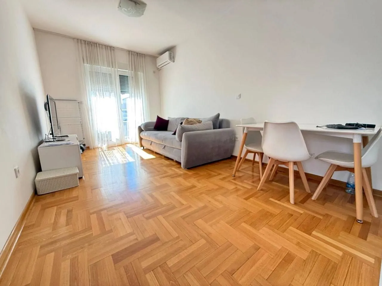 Living room with sofa, dining table, and parquet flooring.