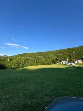 Zelena livada sa pogledom na šumu i okolne kuće. - image 7