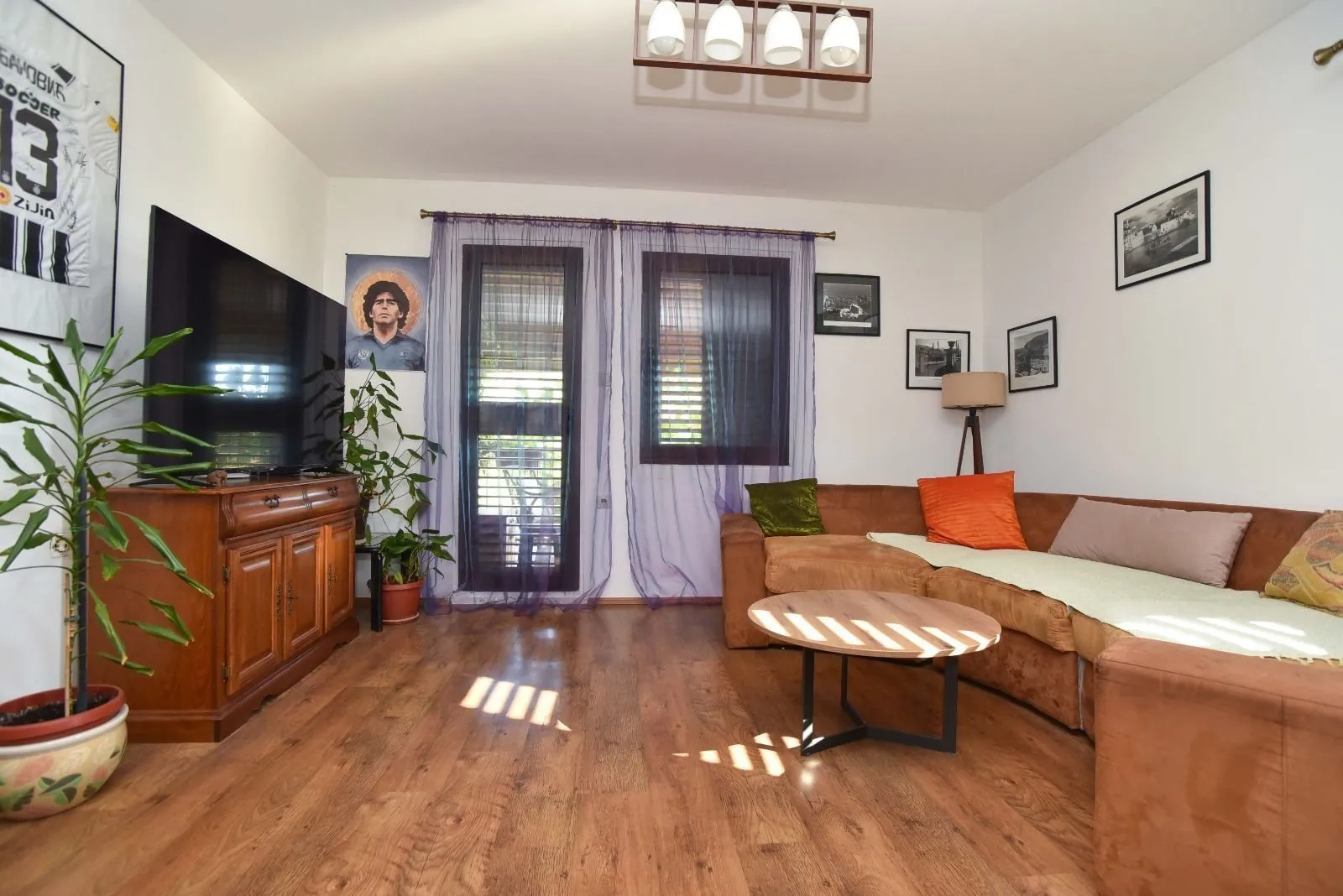Living room with a sofa set, TV, and wooden flooring.