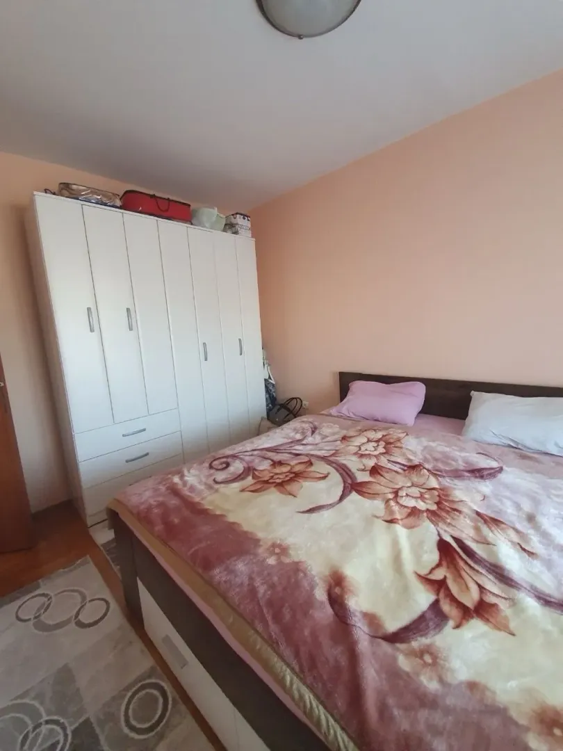 Spavaća soba sa bračnim krevetom i velikim bijelim ormarom.