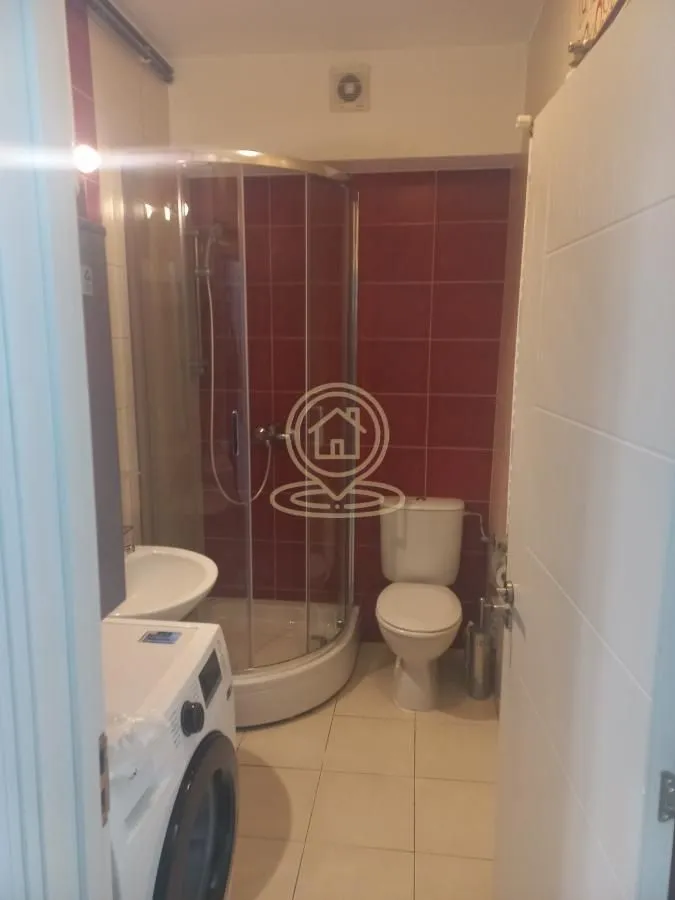 Small bathroom with a shower cabin, toilet, washbasin, and washing machine.