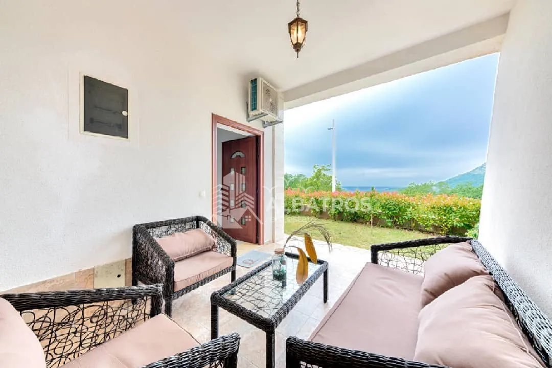 Covered terrace with seating furniture and a view of nature and the sea.
