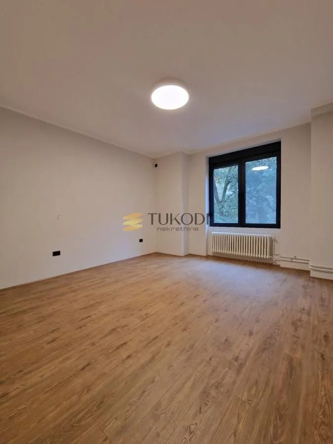 Empty bright room with laminate flooring and a single window.
