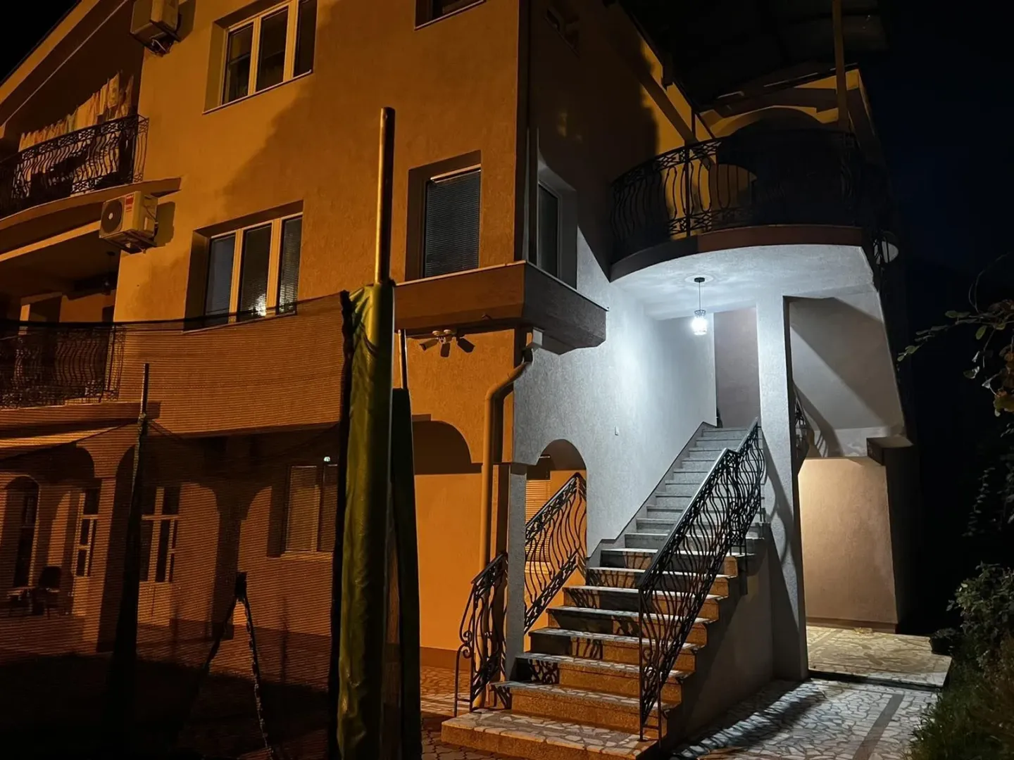 Spoljašnje stepenice i dio fasade stambenog objekta noću.
