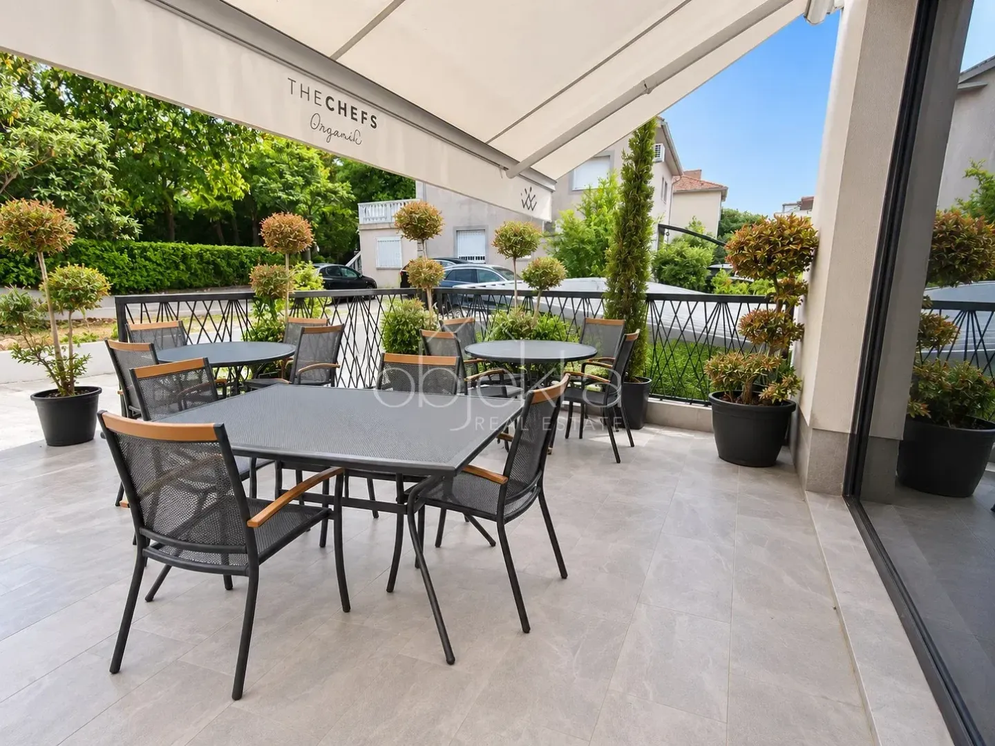 Spacious covered terrace with seating furniture and decorative plants.