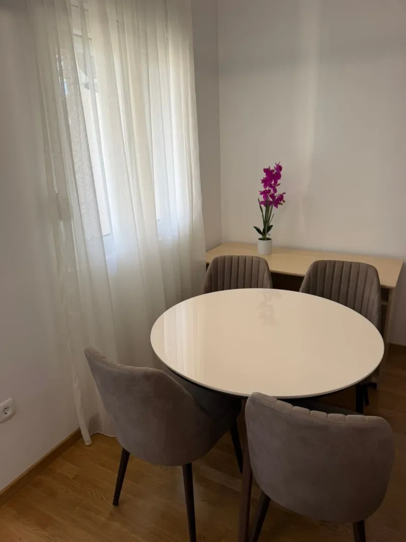 Dining area with a round table and chairs by the window.