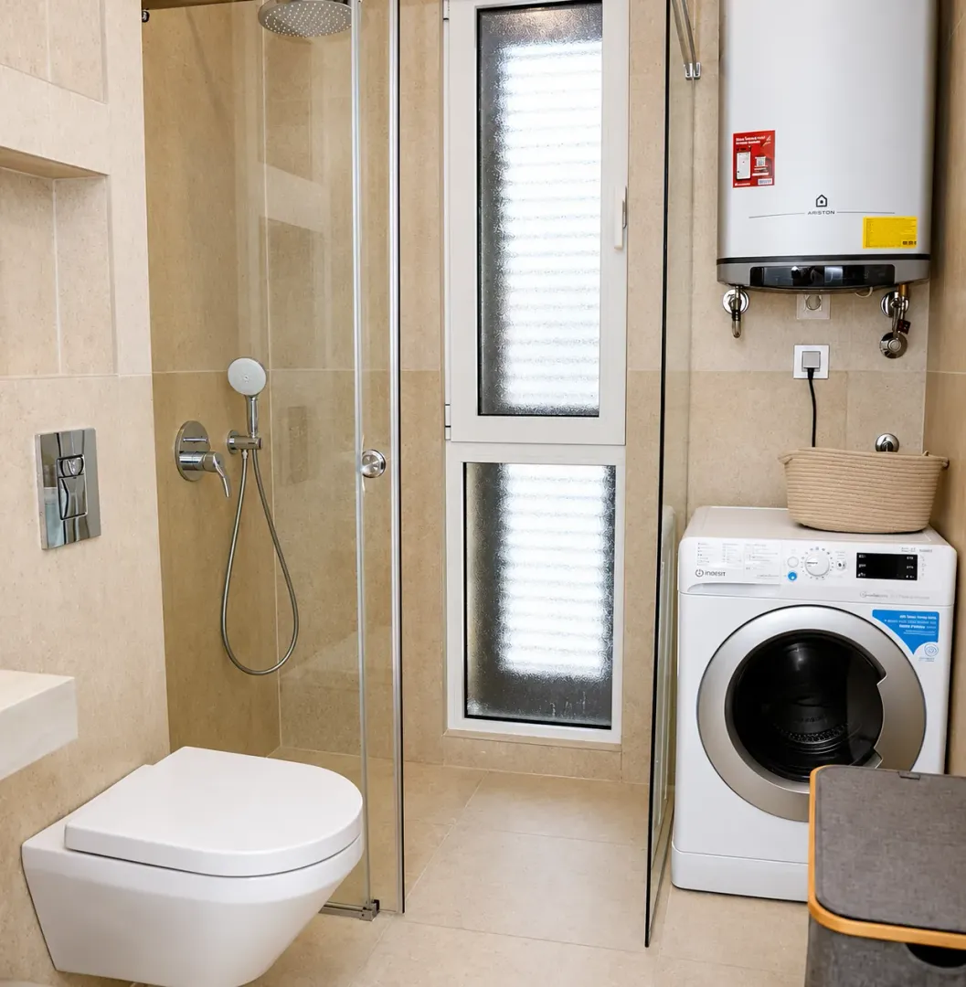 Kupatilo sa tuš kabinom, WC šoljom, bojlerom i veš mašinom.
