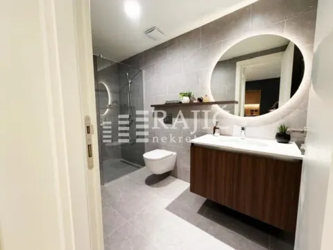 Modern bathroom with a walk-in shower, vanity sink, and illuminated mirror. - image 10