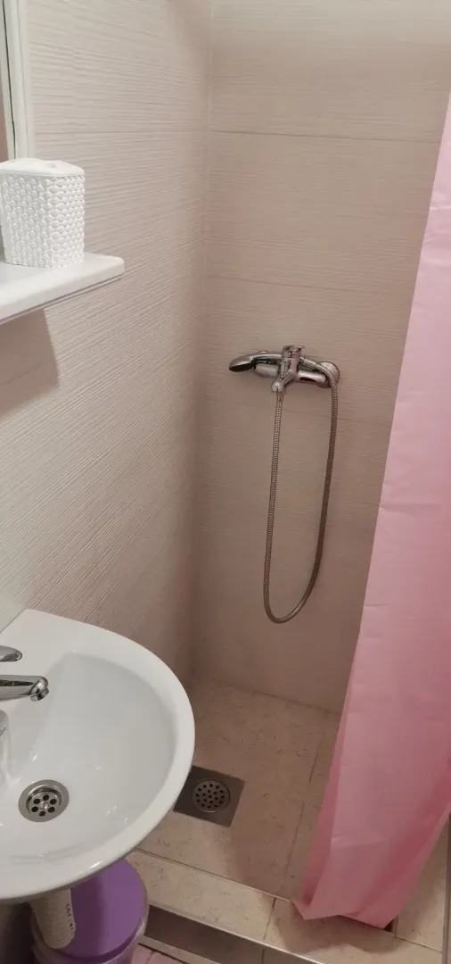 A small bathroom with a shower area and a sink.