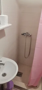 A small bathroom with a shower area and a sink. - image 9