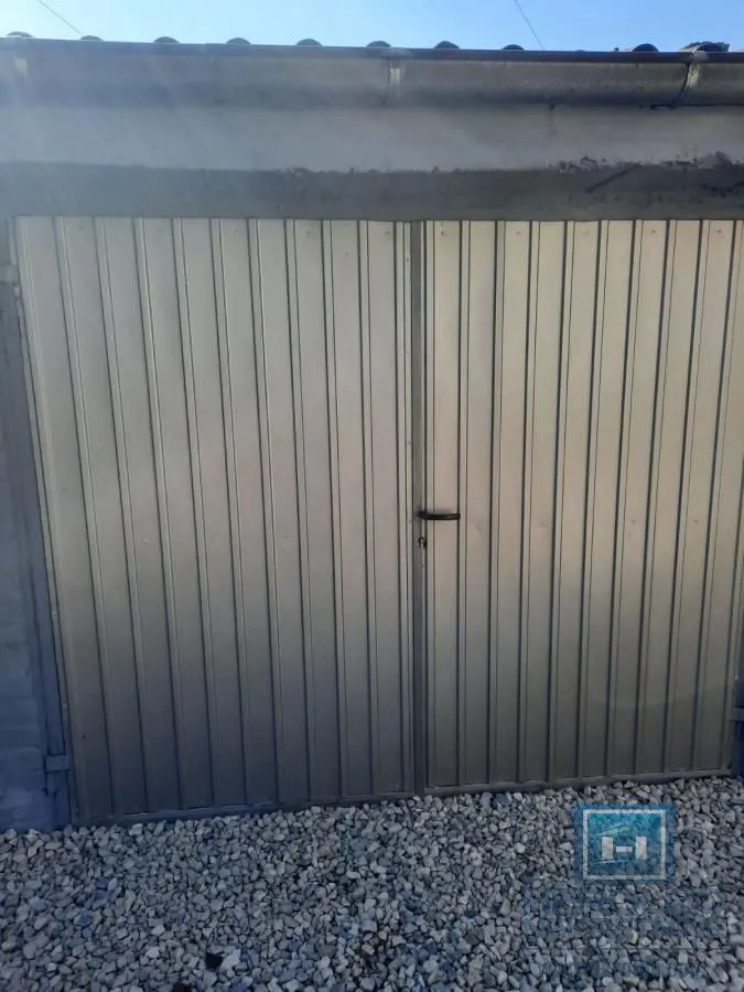 View of metal garage doors with gravel in the yard.