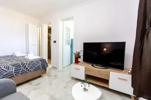Uređena spavaća soba sa krevetom, TV komodom i sopstvenim kupatilom. - image 7