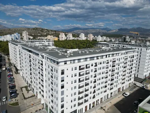 Aerial view of a modern residential building with the surrounding neighborhood and mountains in the background. - image 21