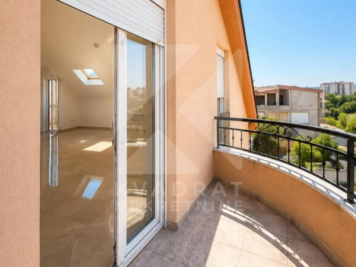 Natkriveni balkon sa metalnom ogradom i pogledom na naselje.