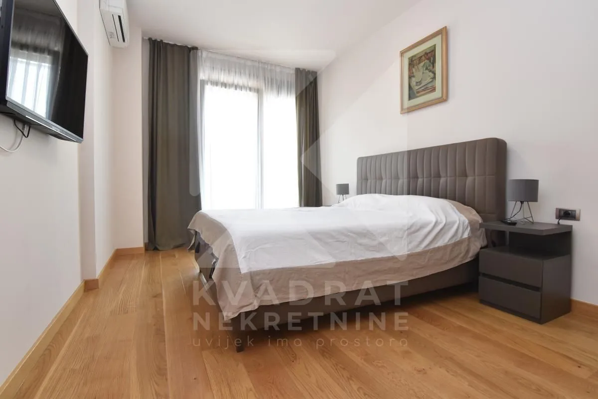 Furnished bedroom with a double bed, nightstands, and a wall-mounted TV.