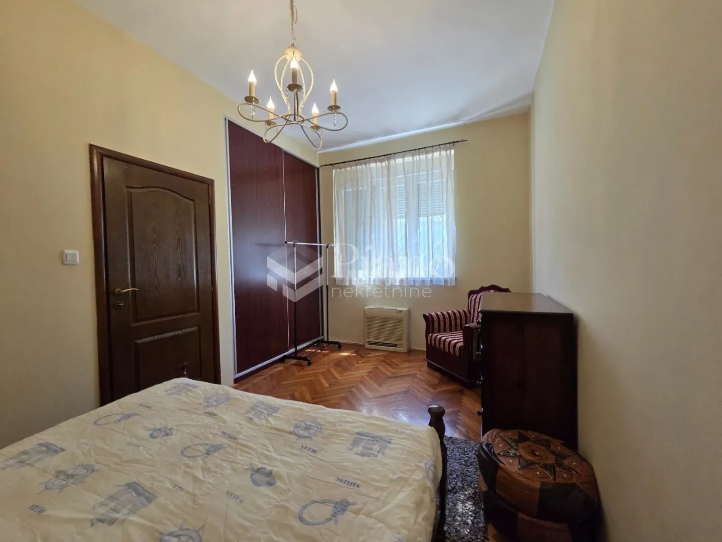 Furnished bedroom with a double bed, wardrobe, and wooden flooring.