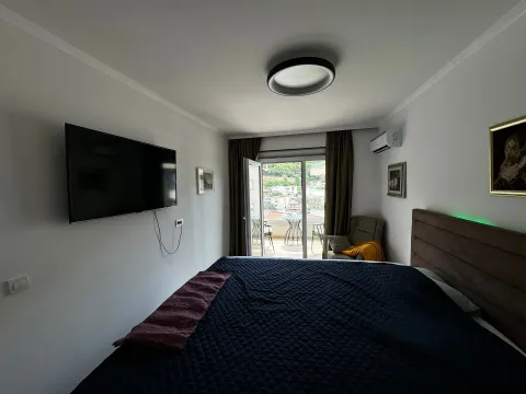 Spavaća soba sa bračnim krevetom, televizorom i izlazom na terasu. - image 12