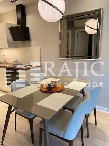 Dining area with a table, chairs, and a wall mirror inside the apartment.
