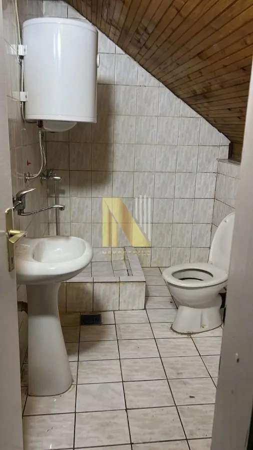 Manje kupatilo sa umivaonikom, wc šoljom i bojlerom pod kosim krovom.