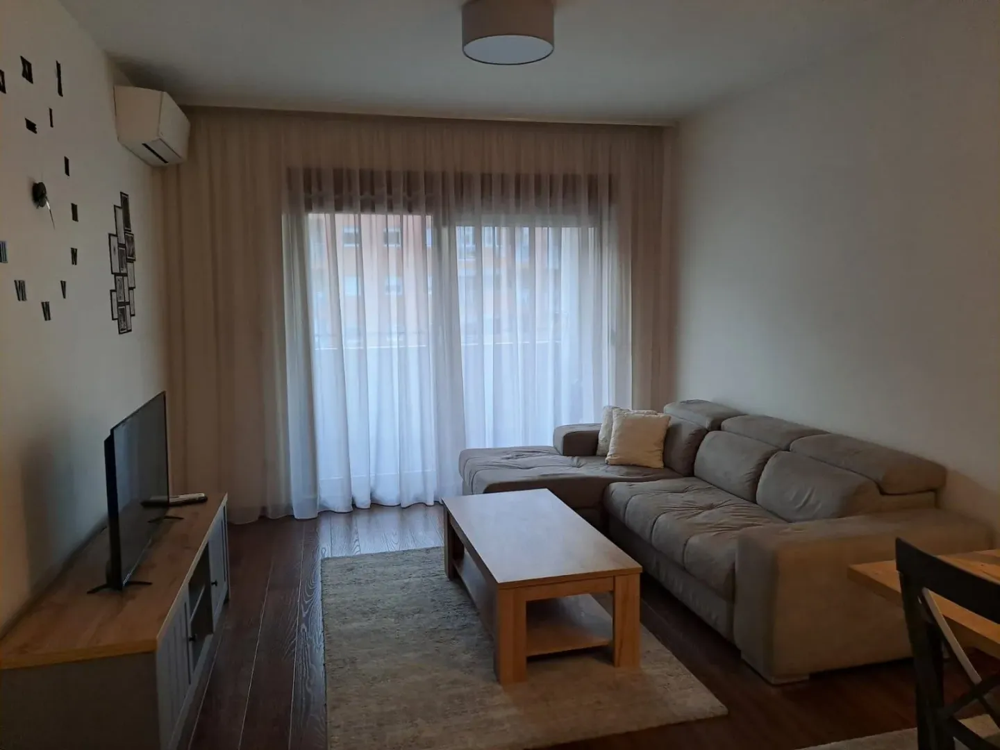 Living room with a corner sofa, television, and dining table.