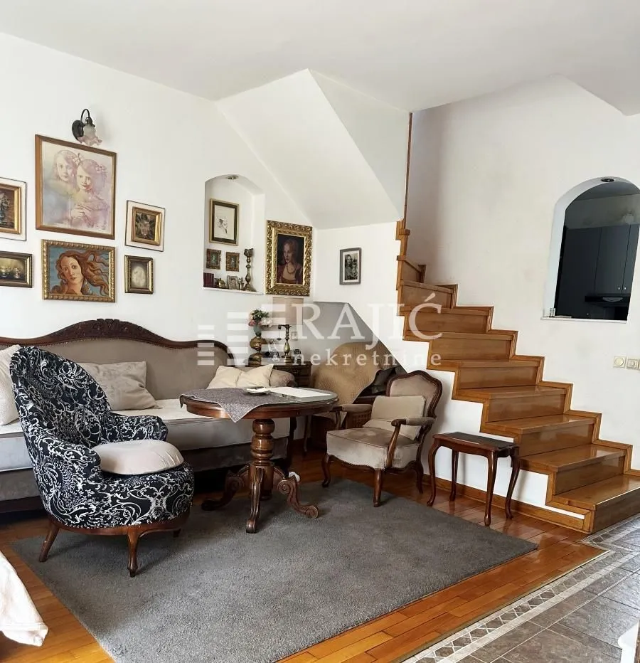 Living room with sofa, wooden staircase, and wall art.